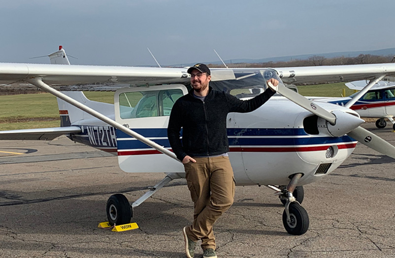 A man leaning against an airplane.